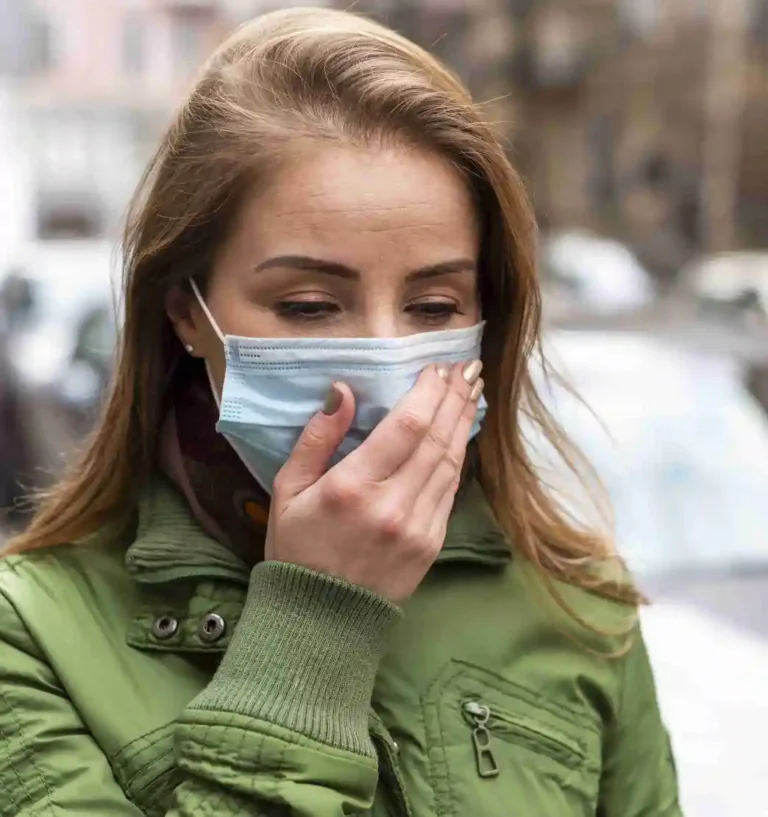 woman wearing mask holding her hand to her face